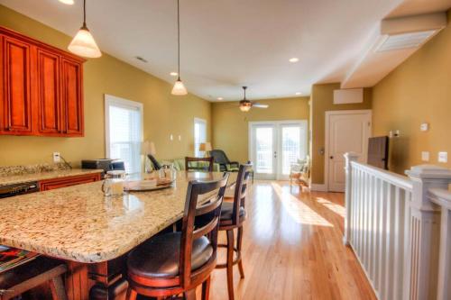 a kitchen and dining room with a large island with chairs at Luxury Townhouse w/ Golf Cart & Private Elevator in Carolina Beach