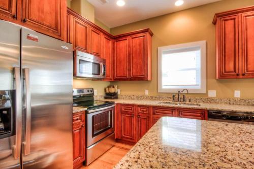 a kitchen with wooden cabinets and a stainless steel refrigerator at Luxury Townhouse w/ Golf Cart & Private Elevator in Carolina Beach