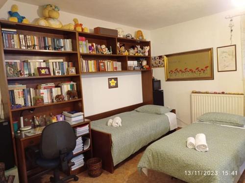 a bedroom with two beds and a book shelf with books at Επικούρειος Ξενώνας 