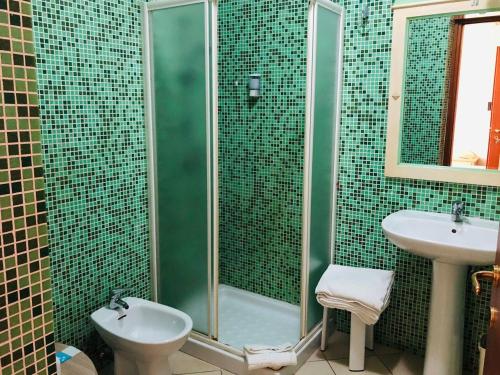 W wyłożonej zielonymi kafelkami łazience znajduje się prysznic i umywalka. w obiekcie Hotel Villabella w mieście San Bonifacio