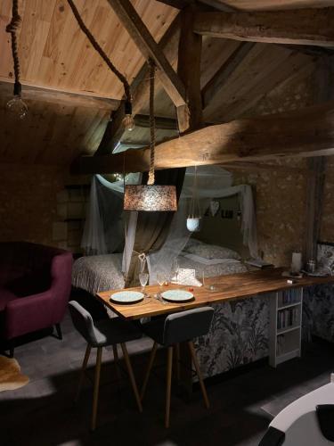 a room with a wooden table and a bed and a desk at L'écrin Dasna in Bourg-sur-Gironde