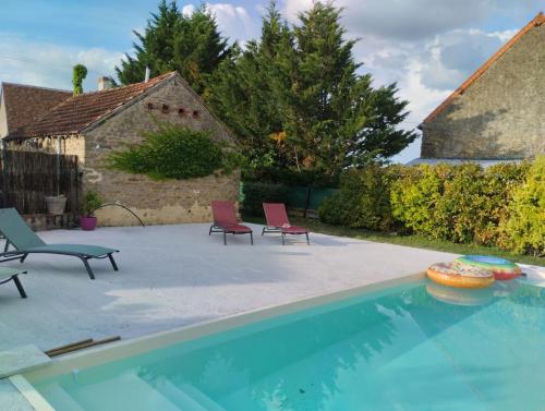 a swimming pool with two chairs next to a house at Maison à proximité du village de George Sand in Nohant-Vic