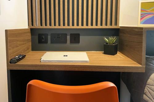 escritorio con ordenador portátil y silla naranja en Deluxe 1 Bed Studio 4A near Royal Infirmary & DMU en Leicester