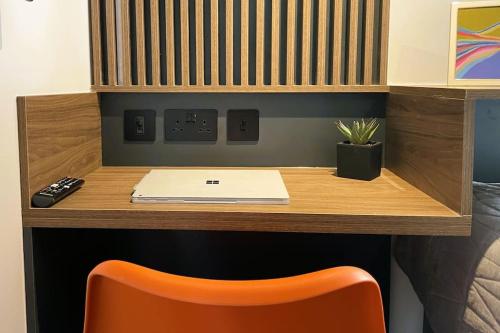 a desk with a laptop computer and a orange chair at Deluxe 1 Bed Studio 4A near Royal Infirmary & DMU in Leicester