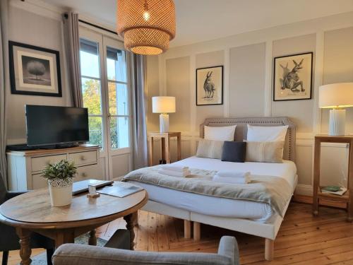 1 dormitorio con cama, mesa y TV en Le Balcon du Port, en Honfleur