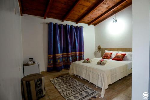 a bedroom with a bed with red pillows and blue curtains at Dar Barka in Kebili