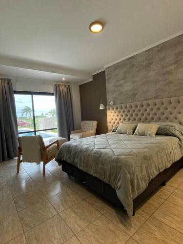 a bedroom with a large bed and a chair at Bitcoins House Los Carpinchos Laguna Brava in Corrientes