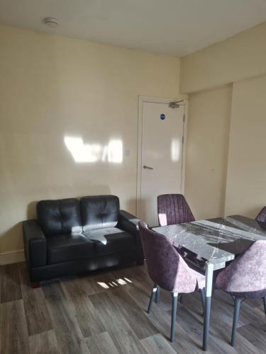 a living room with a black leather couch and a table at Brighton Rd in Derby