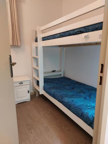 a bedroom with two bunk beds with blue sheets at T2 avec piscine et accès privé à la mer in Sanary-sur-Mer