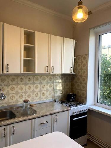 a kitchen with white cabinets and a sink and a window at Cozy flat in the middle of Tbilisi in Tbilisi City