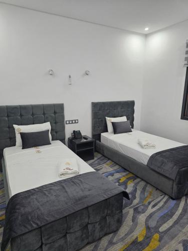 two beds in a room with two bedsskirts at فندق الشموخ Hotel Al Shmokh in Bir Gandouz