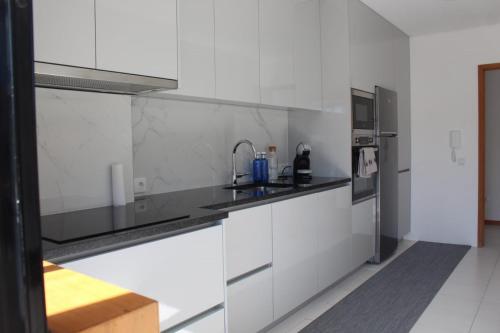 a white kitchen with a sink and a refrigerator at Beach House in Vila do Conde
