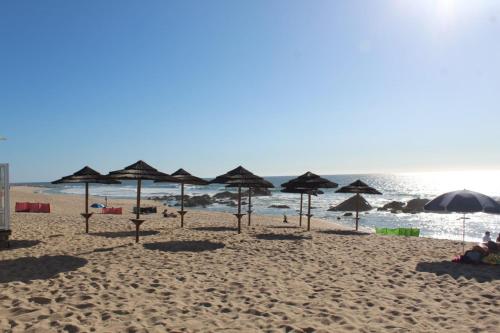 a beach with umbrellas and people on the sand at Beach House in Vila do Conde