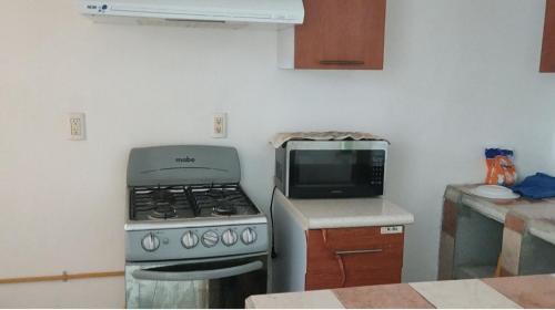 a kitchen with a stove and a microwave at Casa de descanso in Acapulco