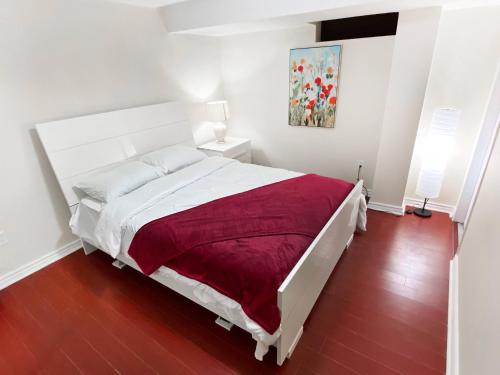 een slaapkamer met een wit bed en een rode deken bij Spacious 2BR Apartment, Large Kitchen, Parking Included in Mississauga