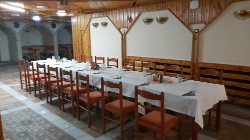 a long table in a room with white tables and chairs at Почивна станция - ТЕЦ Бобов дол in Bistriza