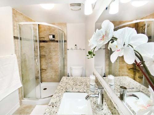 a bathroom with a sink and a shower with white flowers at Spacious 2BR Apartment, Large Kitchen, Parking Included in Mississauga