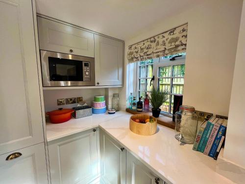 a kitchen with white cabinets and a microwave at Old Post Office in Sherborne