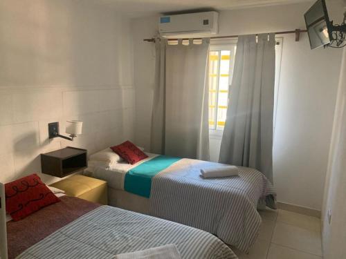 2 camas en una habitación pequeña con ventana en Hostal Camp de Mar en San Bernardo