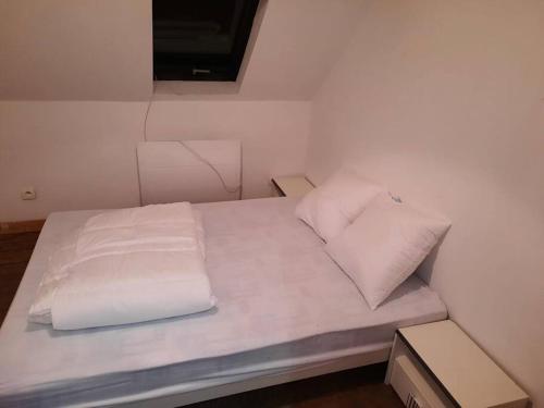 - un lit avec des draps et des oreillers blancs dans l'établissement Agréable maison de pêcheurs avec parking gratuit., à Grand-Fort-Philippe