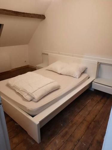 - un lit avec des draps et des oreillers blancs dans l'établissement Agréable maison de pêcheurs avec parking gratuit., à Grand-Fort-Philippe
