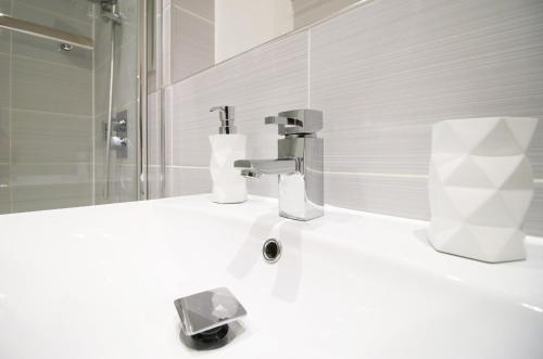 a white bathroom with a sink and a faucet at K Suites - Carnival Court in Bridgwater