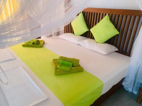 1 dormitorio con 1 cama con almohadas verdes y blancas en Villa Riverside, en Aluthgama