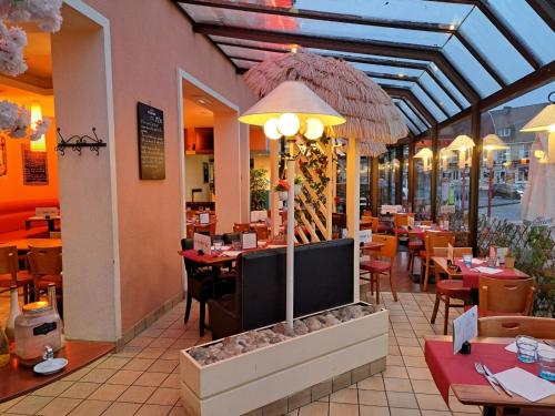 un restaurante con zona de comedor con mesas y sillas en Hôtel Le Phare en Ouistreham