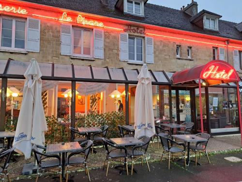 a group of tables and umbrellas in front of a restaurant at Hôtel Le Phare in Ouistreham