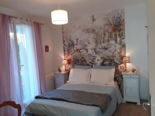 a bedroom with a bed with a painting on the wall at Les Oiseaux chambre d'hôtes in Saint-Florent-sur-Cher