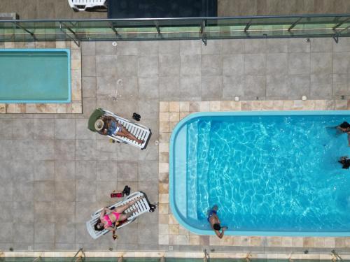 an overhead view of a swimming pool with people sitting around it at Hotel Amaromar in Pontal do Paraná