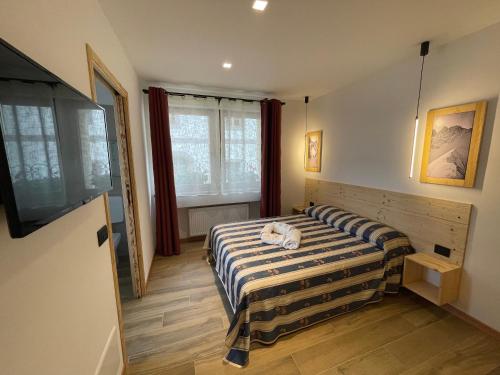 a bedroom with a bed and a television in it at AFFITTACAMERE ALLE ALPI in Malborghetto Valbruna