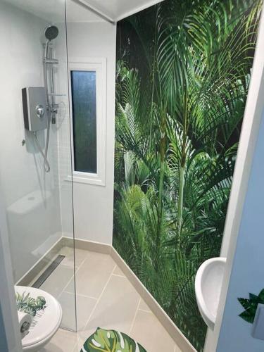 baño con ducha y un mural de plantas en Cosy Jungle Cabin With Bathroom 