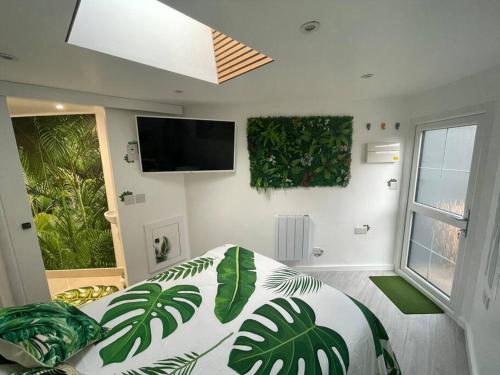 a bedroom with a bed with green plants on the wall at Cosy Jungle Cabin With Bathroom 