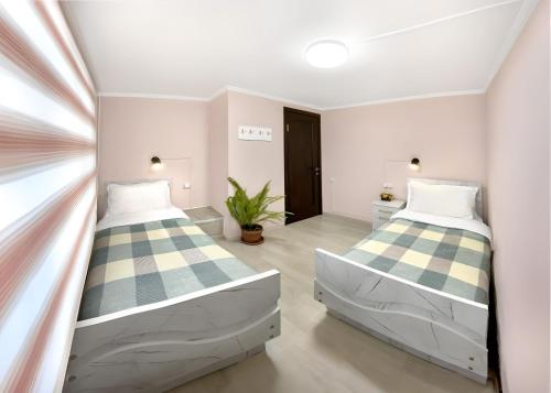 twee bedden in een kamer met een raam bij Guesthouse Liliia in Karakol