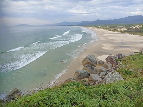 a view of a beach with rocks and the ocean at Dunas Tiny House casa 1 in Florianópolis