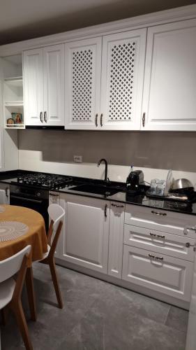 a kitchen with white cabinets and a sink and a table at Freya Residence in Iaşi