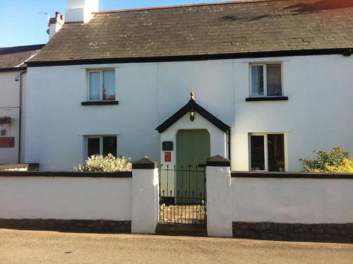 a white house with a green door and a fence at The Old Barn in Barry