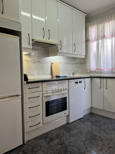 una cocina con armarios blancos y un horno de fogón blanco en Apartamento Oporto en Madrid