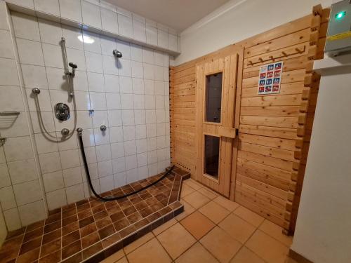 a bathroom with a shower and a wooden wall at Haus Ski & Sun by Globalimmoservice in Bad Kleinkirchheim