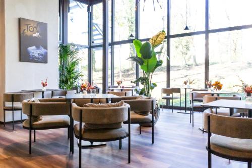 - un restaurant avec des tables, des chaises et de grandes fenêtres dans l'établissement Hotel Lonca - Superior, à Škofja Loka