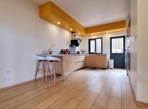 a kitchen with a counter and stools in a room at Villa Le Cyprès classée 4 Etoiles billard, piscine et jacuzzi in Saint-Joseph
