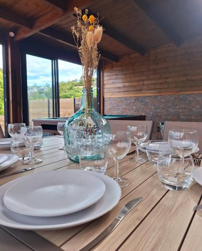 a table with plates and glasses and a vase with flowers at Villa Le Cyprès classée 4 Etoiles billard, piscine et jacuzzi in Saint-Joseph