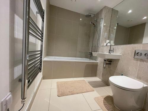 a bathroom with a toilet and a sink and a tub at Lovely 2 Bedroom Apartment London in Woolwich