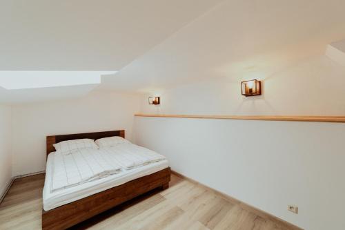 a bed in a room with white walls and wooden floors at Ubytovanie Starý dvor in Spišské Podhradie