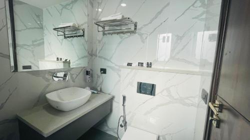 a white bathroom with a sink and a shower at Saltstayz Basil - Near Golf Course Road in Gurgaon
