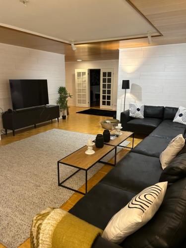 - un salon avec un canapé noir et une table dans l'établissement Villa Mänty 200 m2 Korkeatasoinen kaupunkikoti, à Seinäjoki