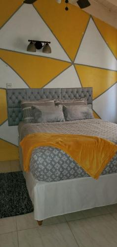 a bedroom with a large bed with a yellow and white wall at Cozy 1-bedroom in a secure area with private beach in Mammee Bay