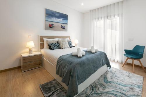 a bedroom with a bed and a blue chair at Zahra Place - Stylish Flat in Nazaré