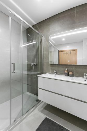 a bathroom with a white sink and a shower at Zahra Place - Stylish Flat in Nazaré
